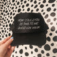 Black cap with white text held against a black and white patterned background