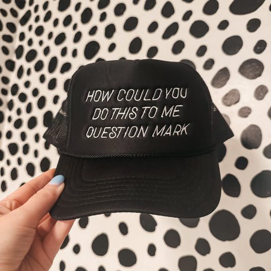 Black cap with white text held against a black and white patterned background